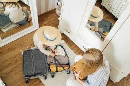 women packing a gray suitcase