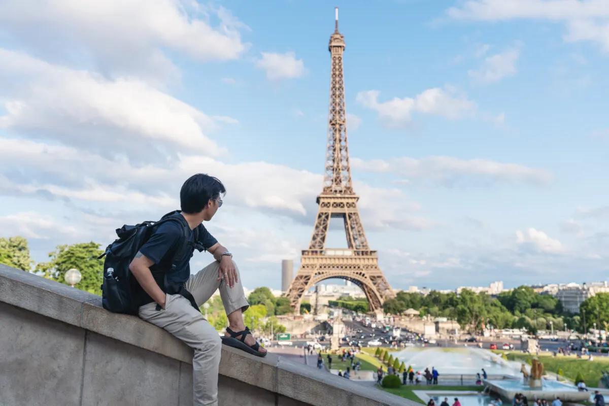 a man with backpack looking at Eiffel tower, famous landmark and travel destination in Paris, France. Traveling in Europe in summer