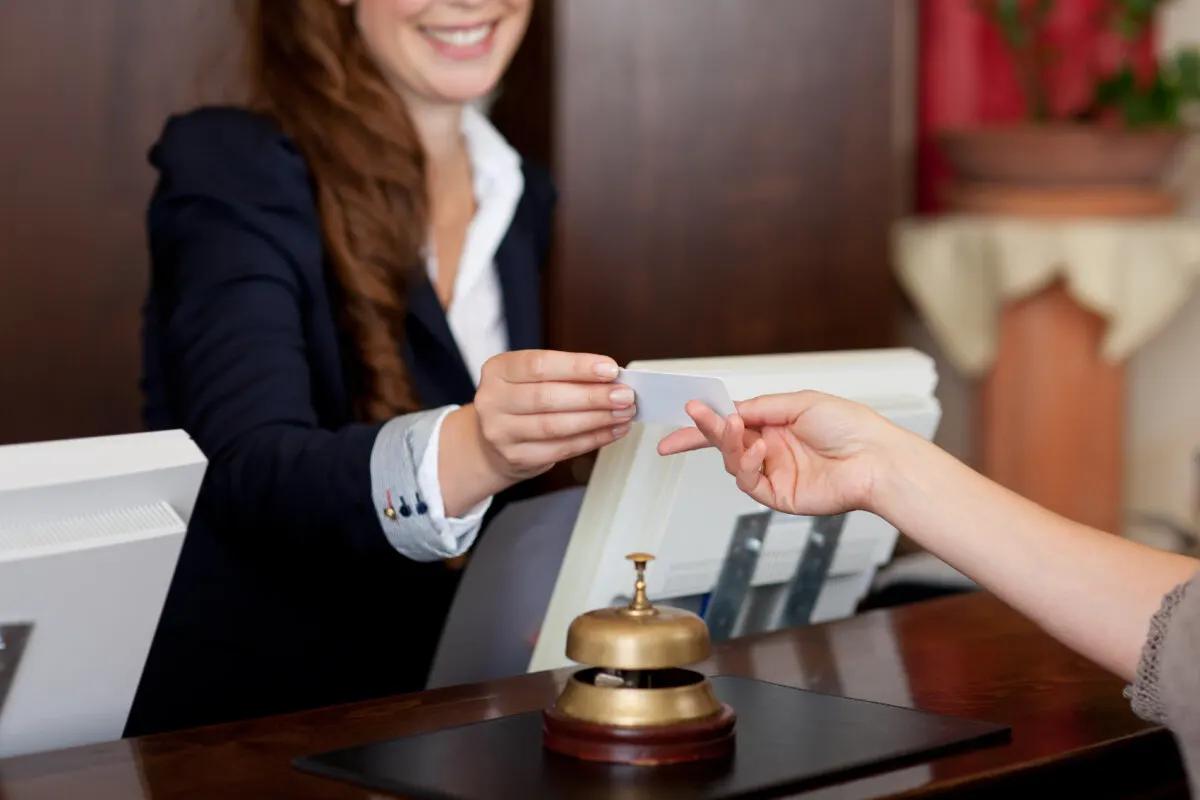 Hotel receptionist handing a hotel room key to a guest