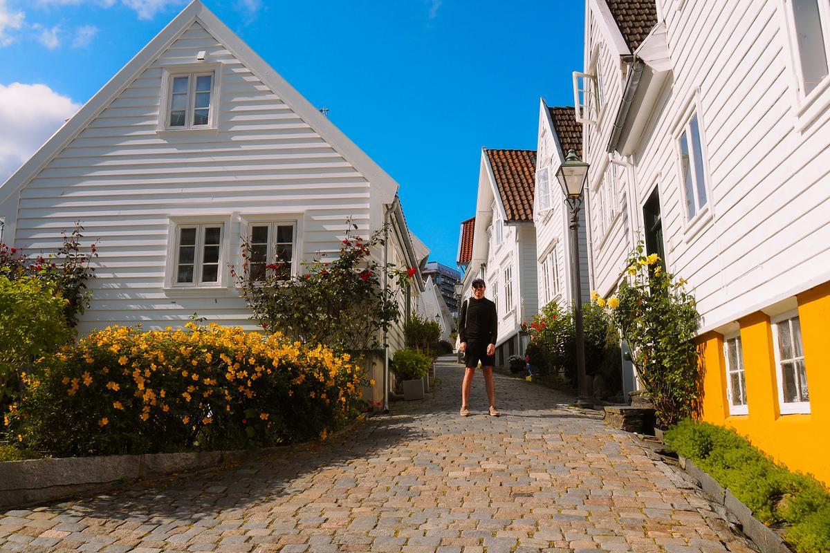 Author, Kyle Kroeger on a charming cobblestone street in Old Town Stavanger, Norway, with white wooden houses and flowers