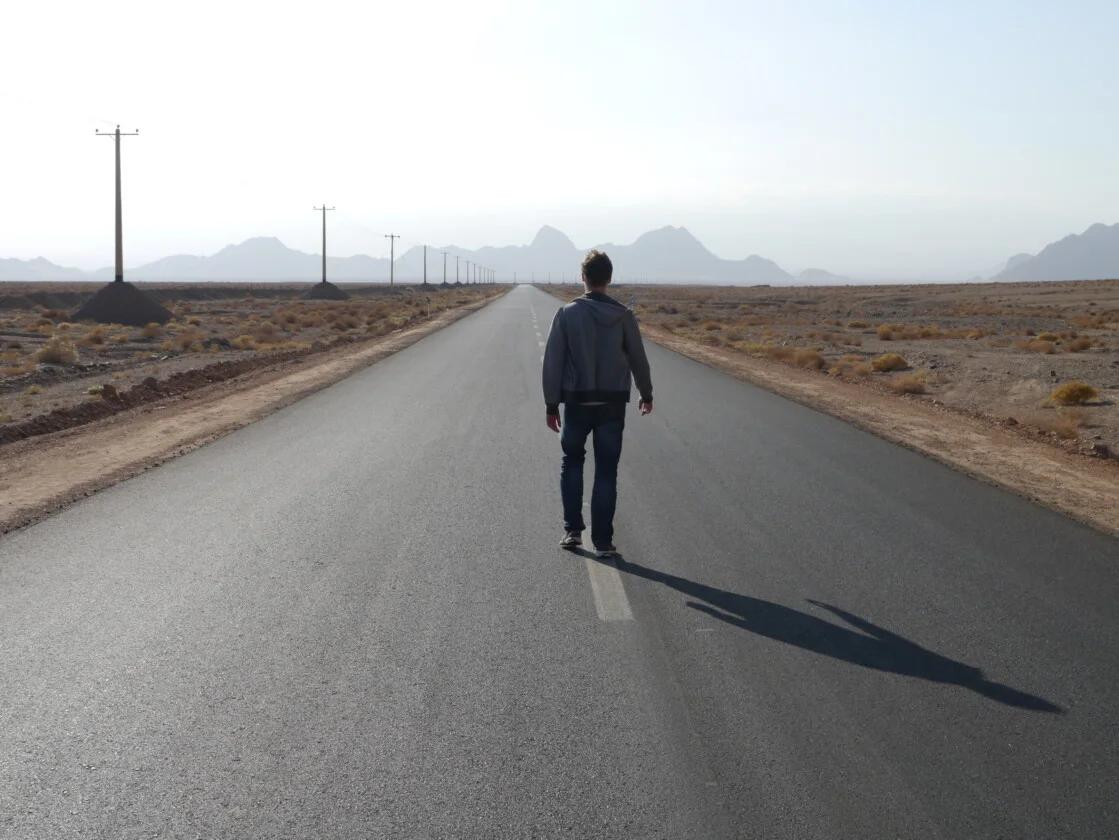 Stuart Jameson, a lone hitchhiker walking down the center of the road in Iran