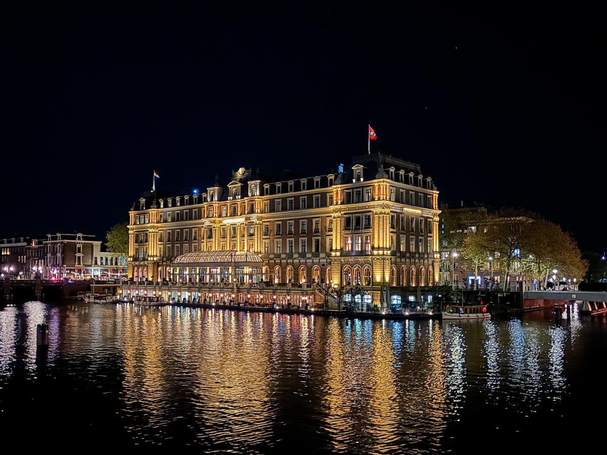 Amstel Hotel illuminated at night in Amsterdam, showcasing historic luxury and architectural grandeur