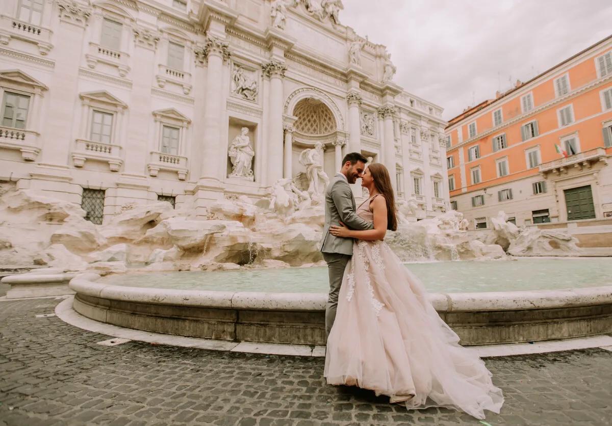 Bride and groom taking a photo in front of Trevi Fountain in Rome, Italy