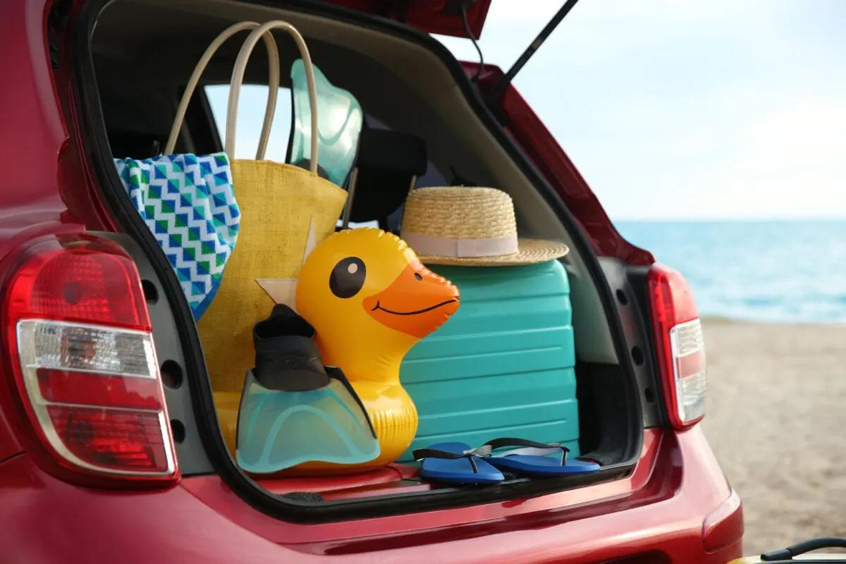 Red car with luggage on beach, closeup for summer vacation trip