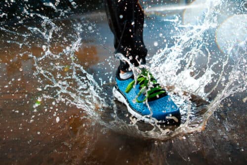 Single runner running in rain and making splash in puddle