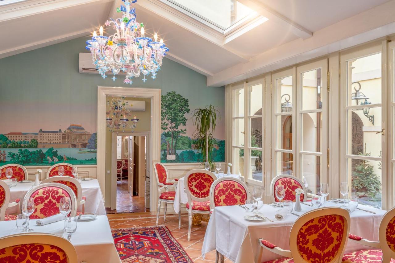 Alchymist Grand Hotel dining room with ornate paintings, antique mirrors, and crisp white tablecloths.