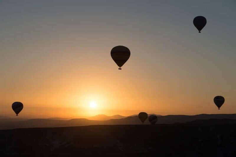 Four hot air balloons against a sunrise.