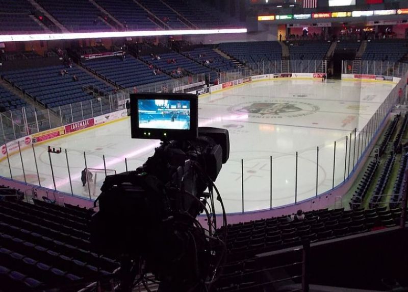Bird's eye view of a vibrant hockey game in a brightly lit arena Close-up action of players on the hockey rink Comprehensive view of the intense hockey game from a medium distance