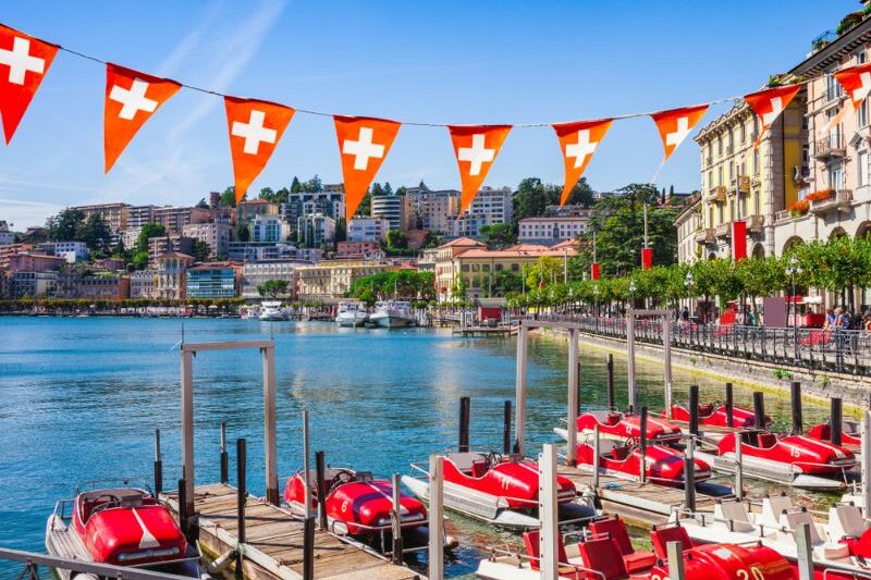 Panorama view of the lake Lugano, mountains and city Lugano, Ticino canton, Switzerland. Scenic beautiful Swiss town with luxury villas.