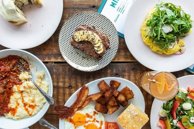 Rustic wooden table set with a charming display of delectable dishes, perfect for a leisurely brunch or a hearty breakfast at Miller's All Day restaurant.