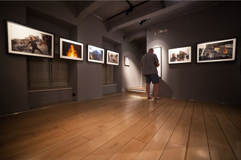 1. "Person admiring artwork in cozy, well-decorated room" 2. "Person studying vibrant, colorful artwork in modern room" 3. "Person lost in thought in room filled with personal memories and mementos"