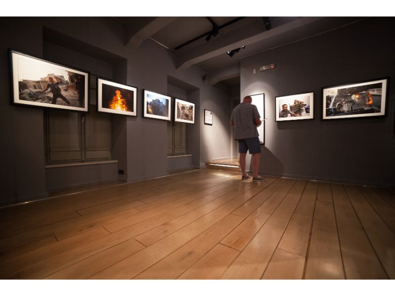 1. "Person admiring artwork in cozy, well-decorated room" 2. "Person studying vibrant, colorful artwork in modern room" 3. "Person lost in thought in room filled with personal memories and mementos"