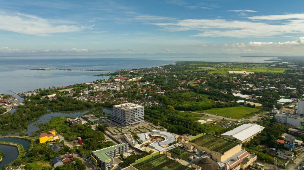 Aerial view of bustling Bacolod City, Philippines showcasing urban environment, lush greenery, local architecture, busy streets, and scenic coastlines.