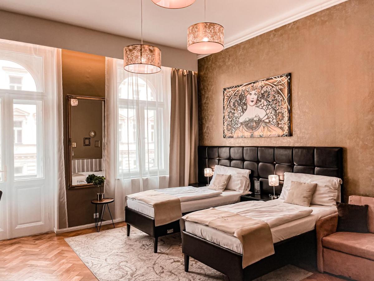 "Cozy twin beds in a well-lit bedroom with elegant decor at the Alfons Boutique Hotel"