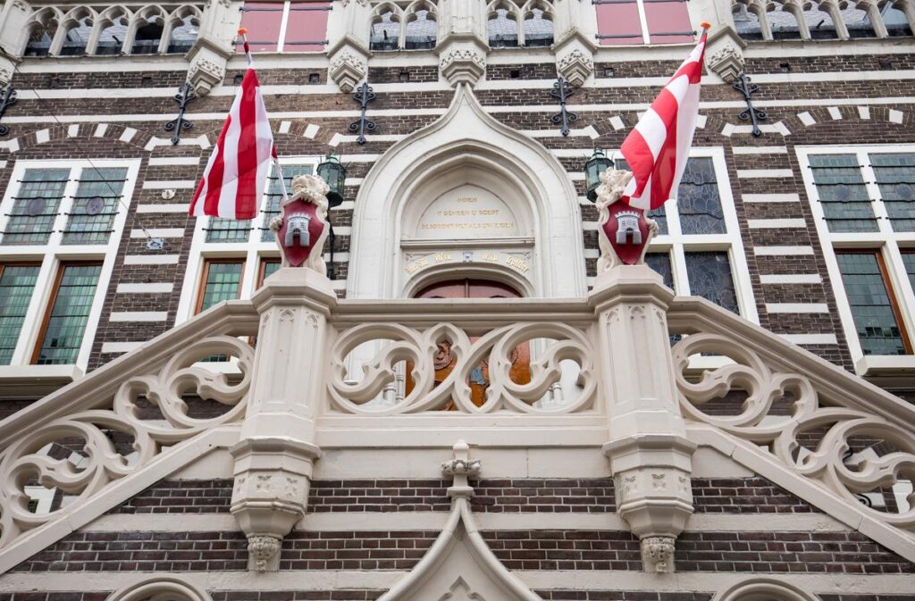 Alkmaar historic city hall facade with Dutch flags, ornate stonework, and Gothic architectural details.
