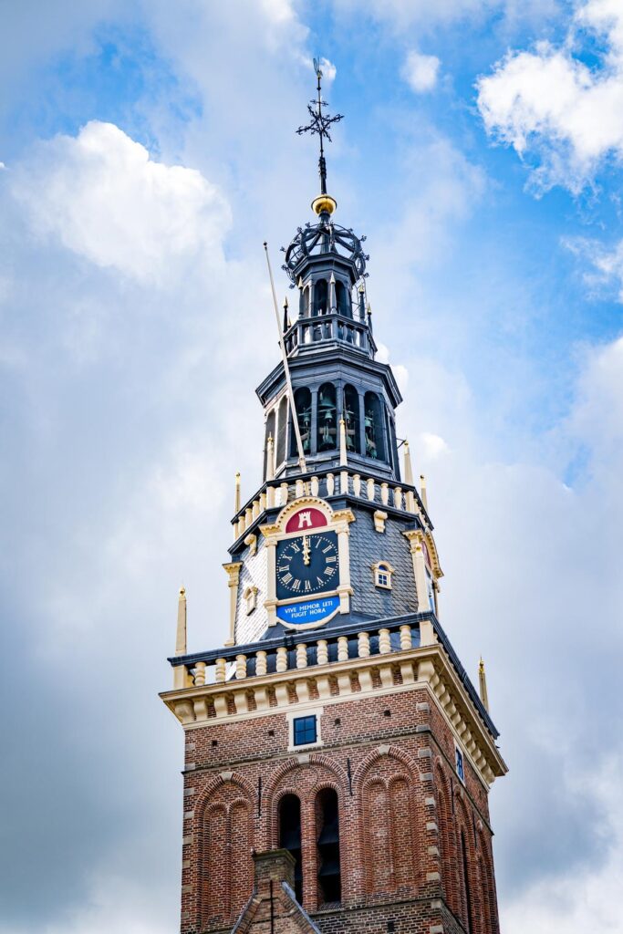 Historic Alkmaar town hall tower with intricate clock against a cloudy sky