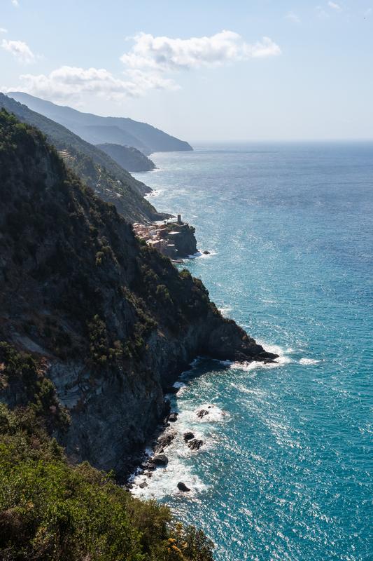 Vernazza vista, Cinque Terre coast, Monterosso trail, Italy; rocky cliffs, azure sea.