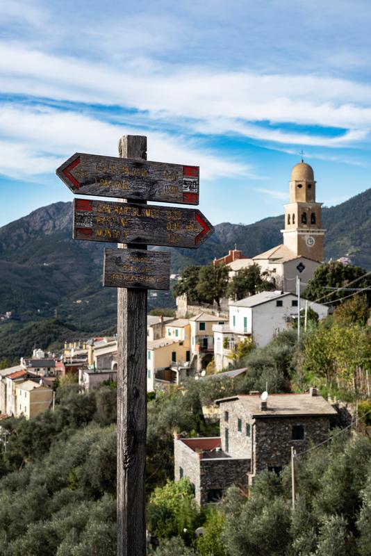 Cinque Terre hiking trail signpost with directions, Italian village, mountains