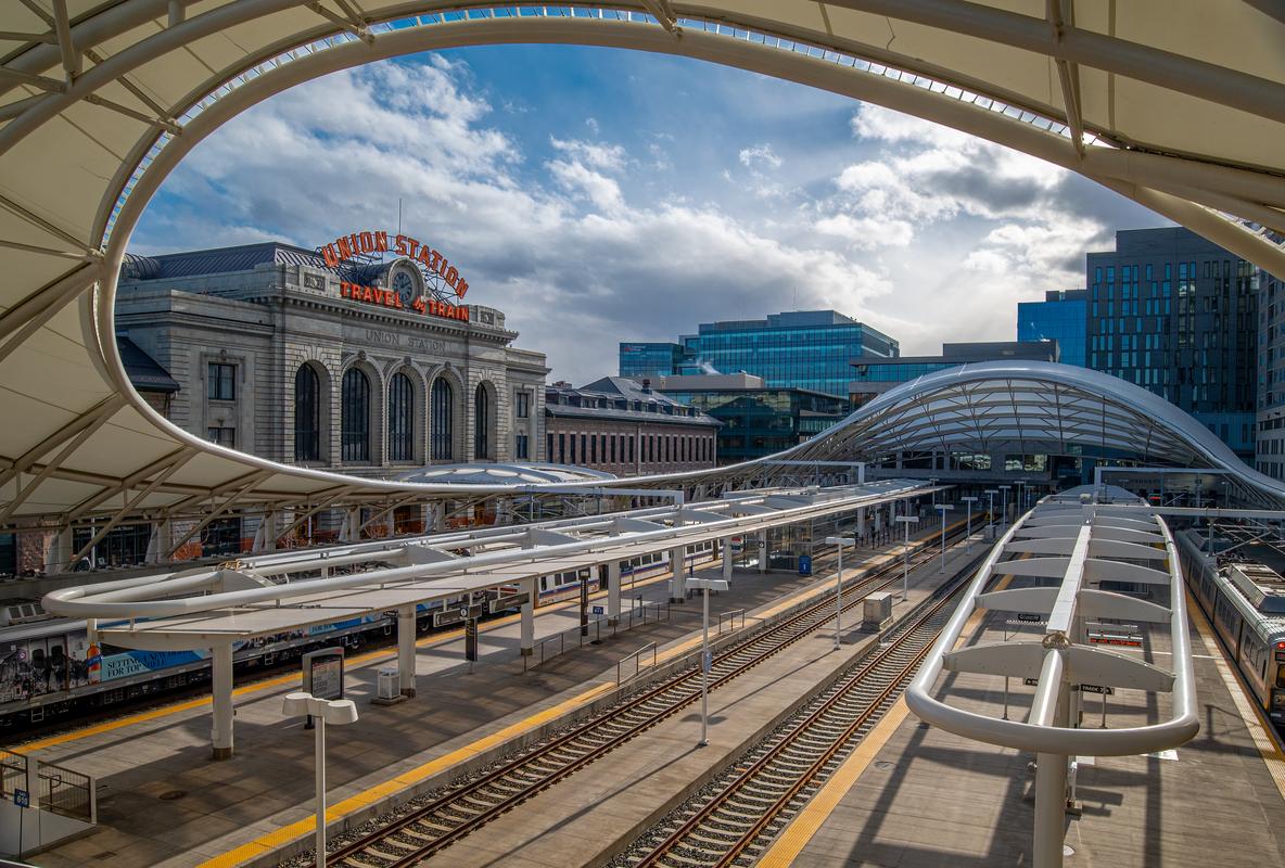 Union Station in Denver, Colorado, featuring the Travel by Train sign and modern urban architecture.