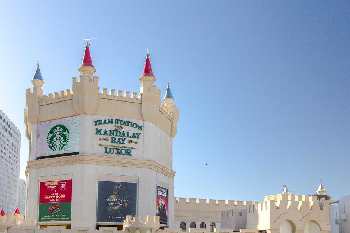 Excalibur Tram Station in Las Vegas features castle-themed architecture and banners, including Starbucks.