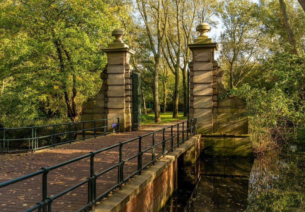 Autumn view at Flevopark Amsterdam with historic gate pillars leading to foliage-rich area.