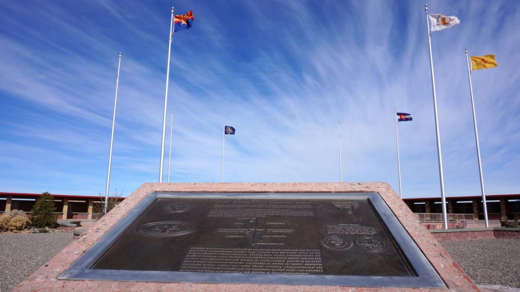 Flags above Four Corners Monument under a clear high-desert sky