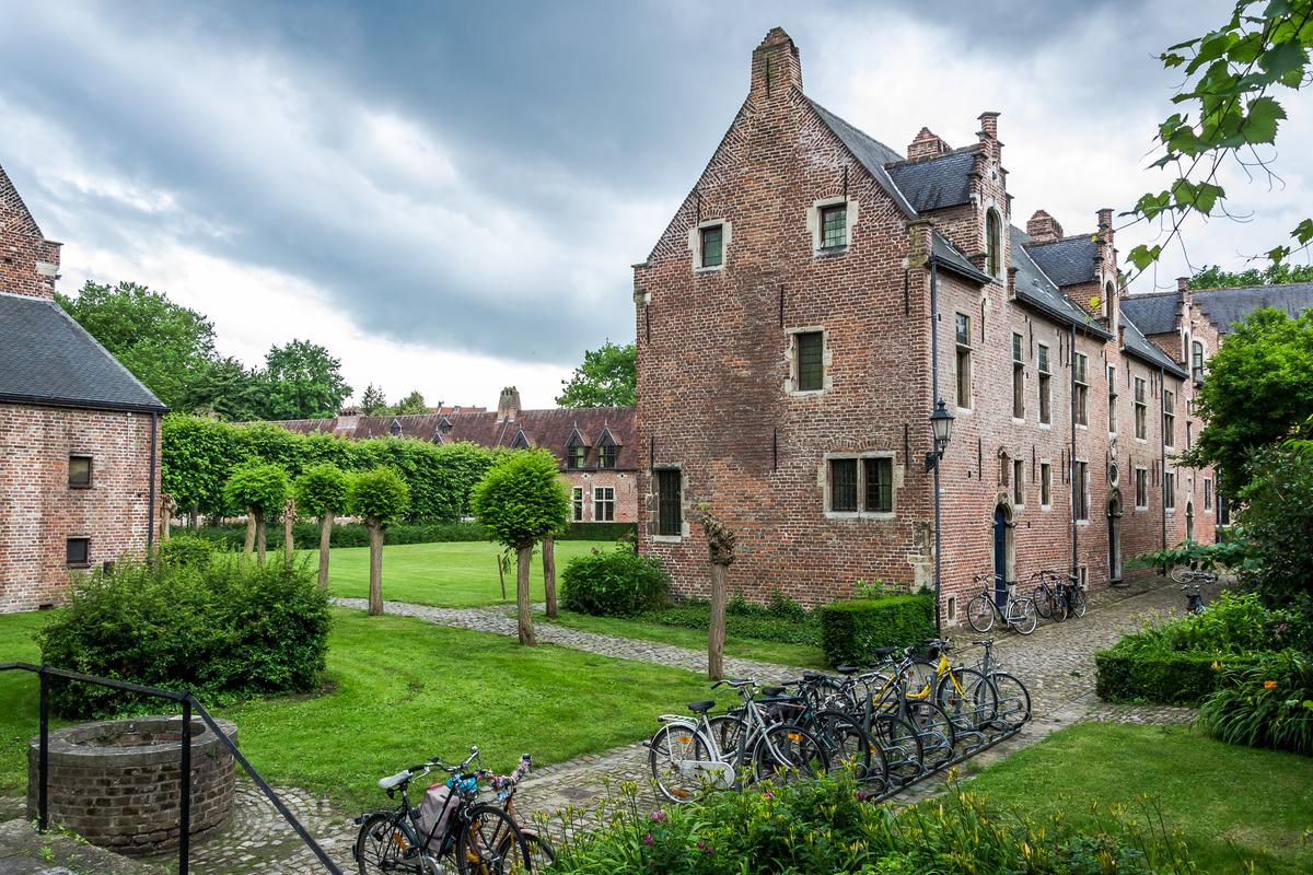 Charming view of Groot Begijnhof, Leuven, Belgium, with traditional brick houses, cobblestone paths, and lush greenery.