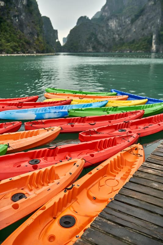 Colorful kayaks lined up on a pier near Ha Long Bay