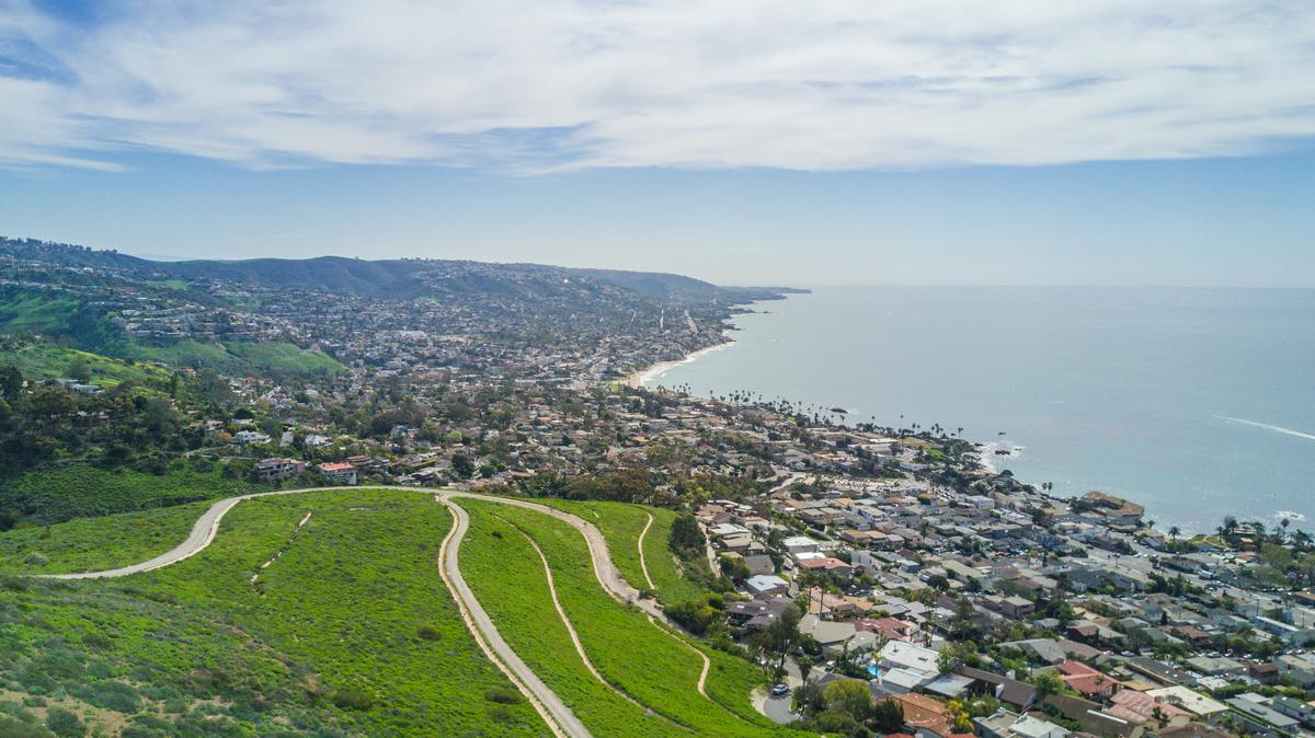 Aerial view of Laguna Beach coastline and residential area in sunny California landscape.