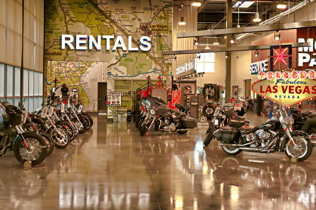 Harley Davidson motorcycle rental shop in Las Vegas with diverse bikes, Welcome to Fabulous Las Vegas sign, and map mural.