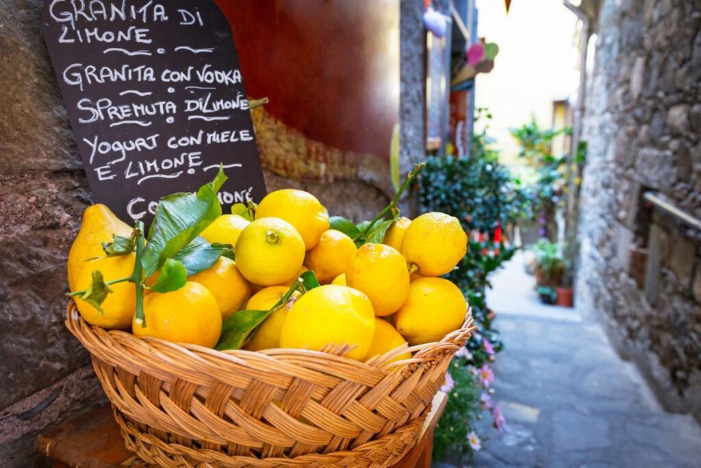Fresh lemons in wicker basket on Corniglia street, Italy. Vibrant citrus, travel, and Italian culture concept. #LemonBasket #CornigliaItaly #TravelPhotography