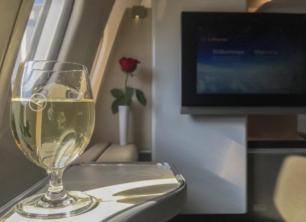 Lufthansa A340-600 luxury flat suite with champagne glass and welcome screen.