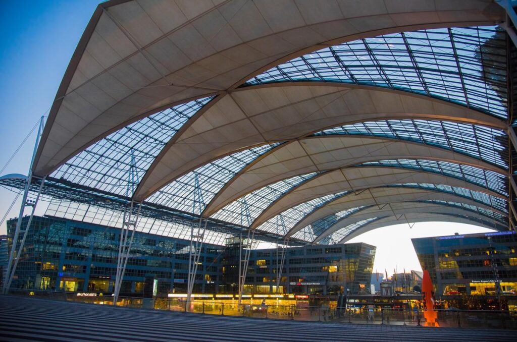 Breathtaking sunset at Munich Airport with iconic architectural canopy and vibrant evening sky hues.