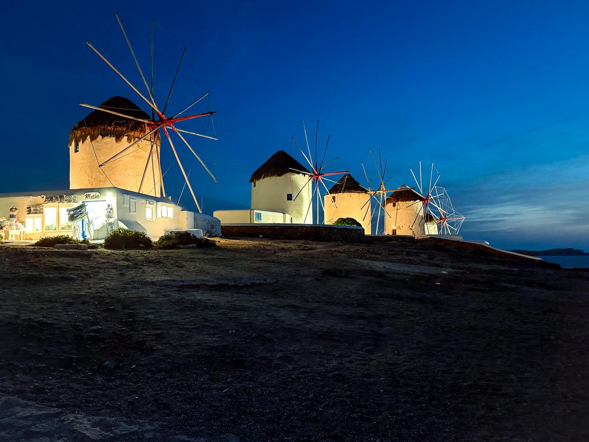 Mykonos windmills illuminated at night, iconic Greek island landscape