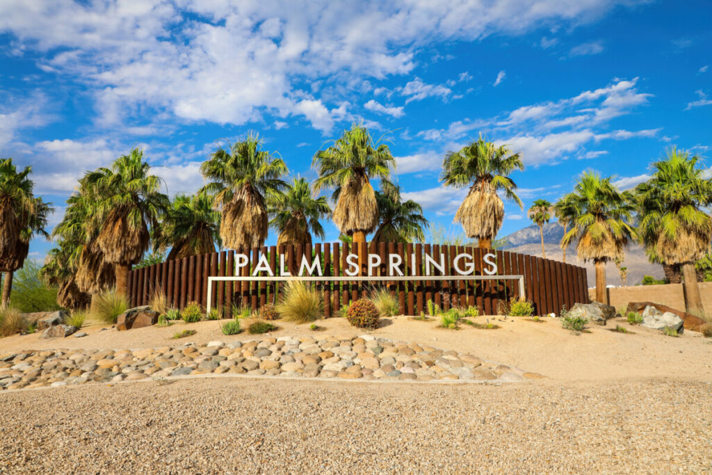 Palm Springs welcome sign surrounded by desert palms and mountains