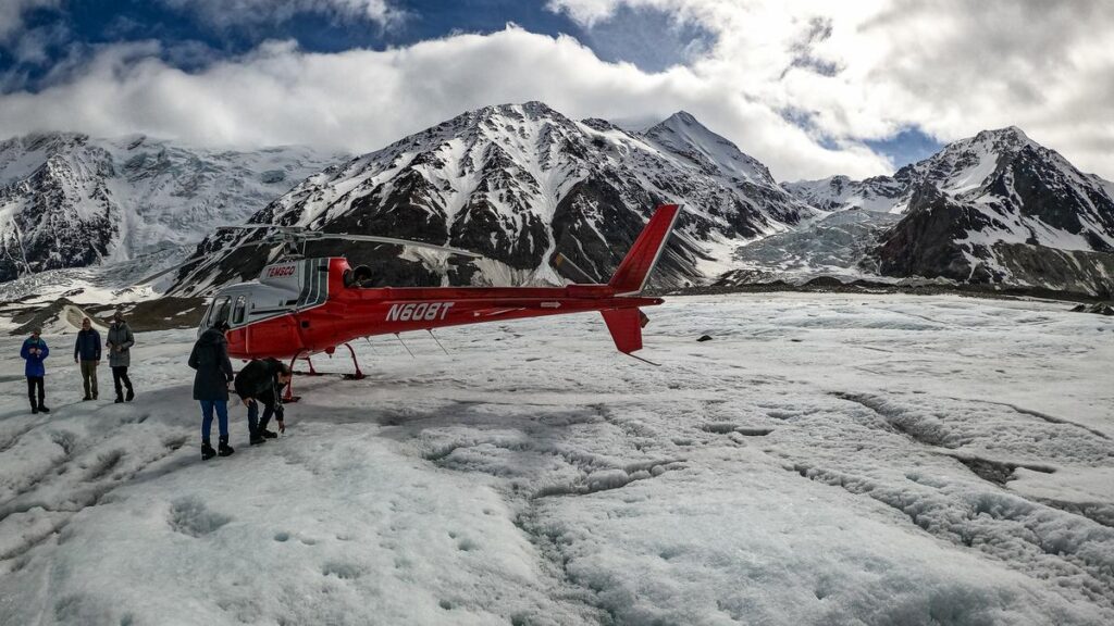 Red helicopter from Temsco with tail number N608T against snow-capped mountains and glacial landscapes in Denali National Park.