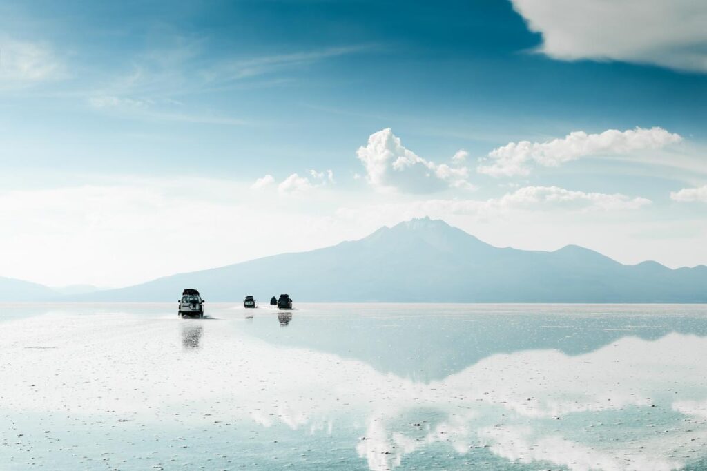 Off-road vehicles on Salar de Uyuni salt flats with mountain backdrop