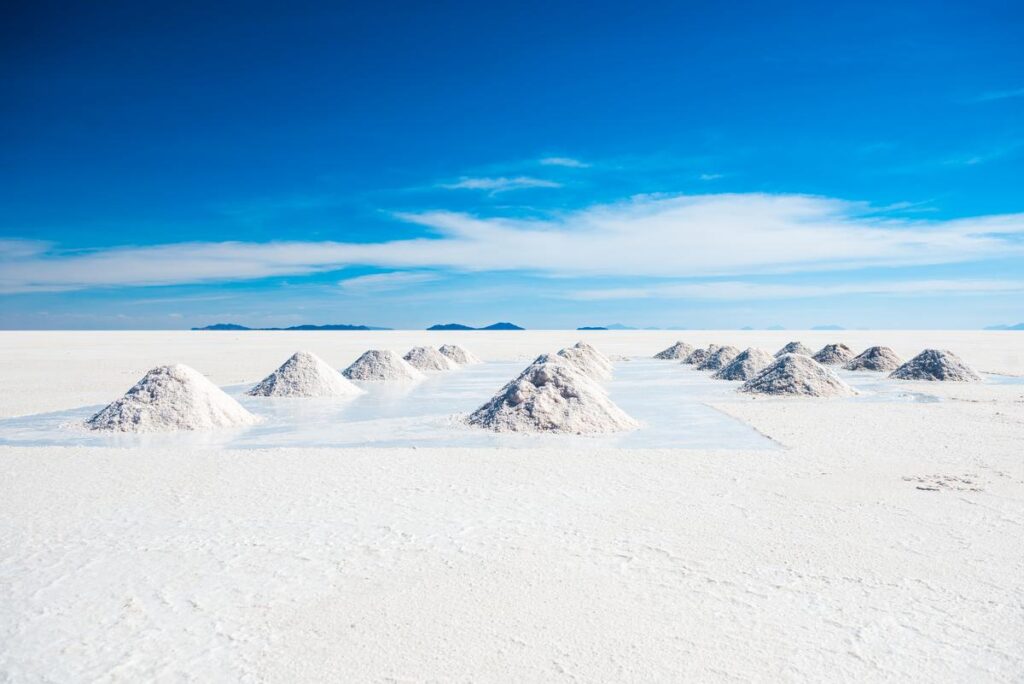 Salt piles on Salar de Uyuni, Bolivia under clear blue skies, vast white salt flats horizon.