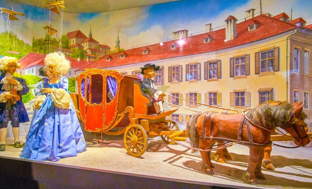 Salzburg Marionette Theater display with historical costume puppets and cityscape backdrop.