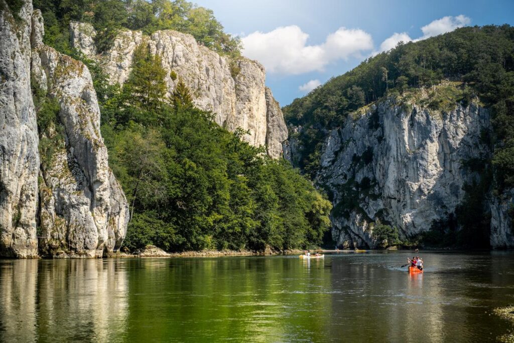 Kayakers in Danube Gorge, Kelheim, Bavaria, flanked by limestone cliffs and lush greenery.