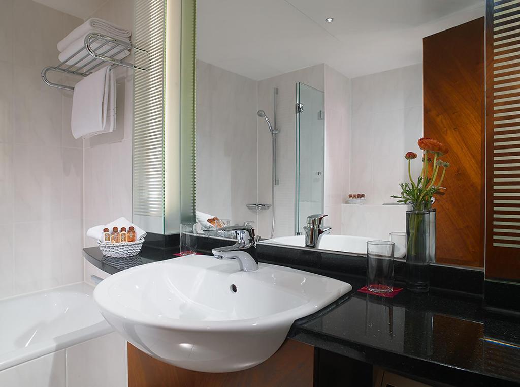 White porcelain sink with rectangular mirror in modern bathroom at Sheraton Carlton Hotel Nuremberg.