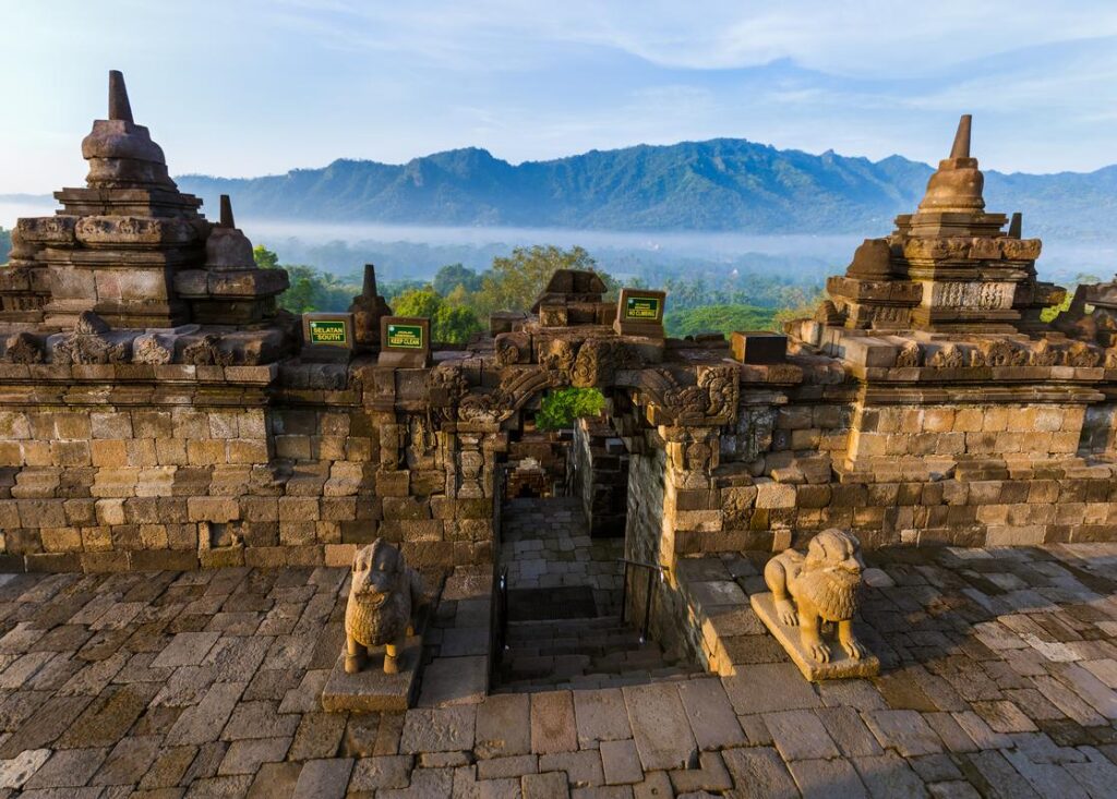 Borobudur stupas at sunrise with mist over the surrounding hills
