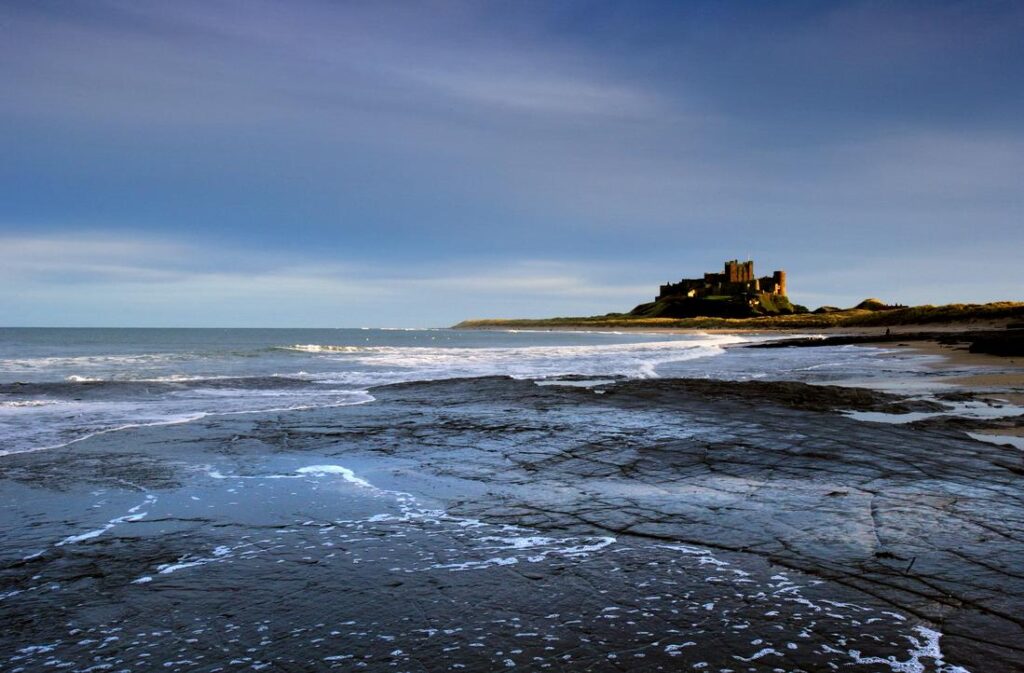 Sunset light over Bamburgh Castle and the surrounding Northumberland landscape