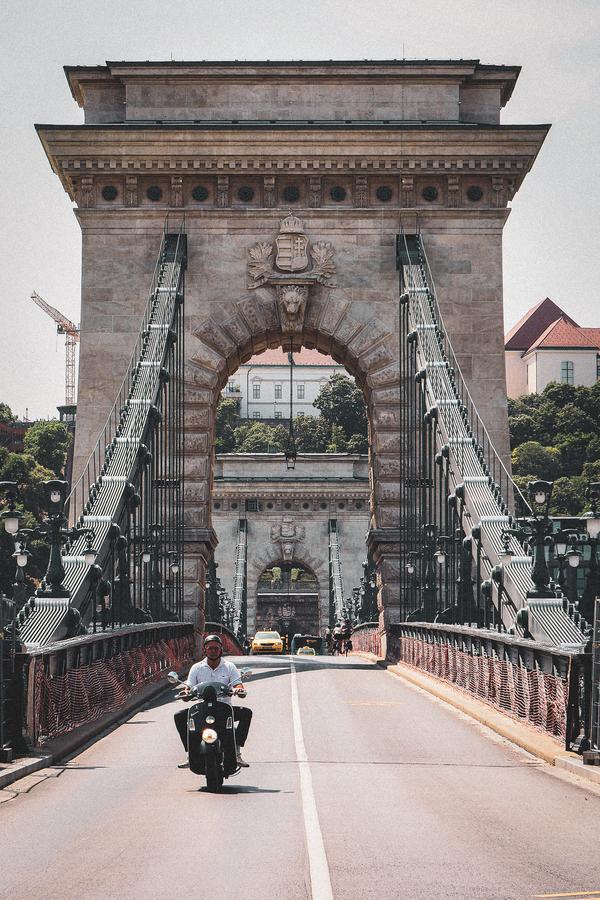 Motorcyclist crossing Széchenyi Chain Bridge Budapest, historical architecture, vertical view
