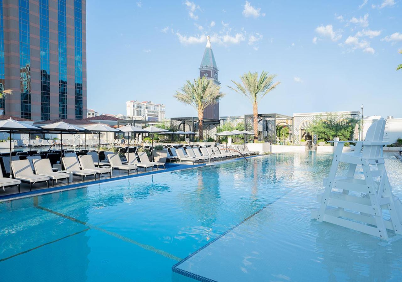 Luxurious swimming pool at The Venetian Las Vegas with a towering modern building in the background and lush greenery around.