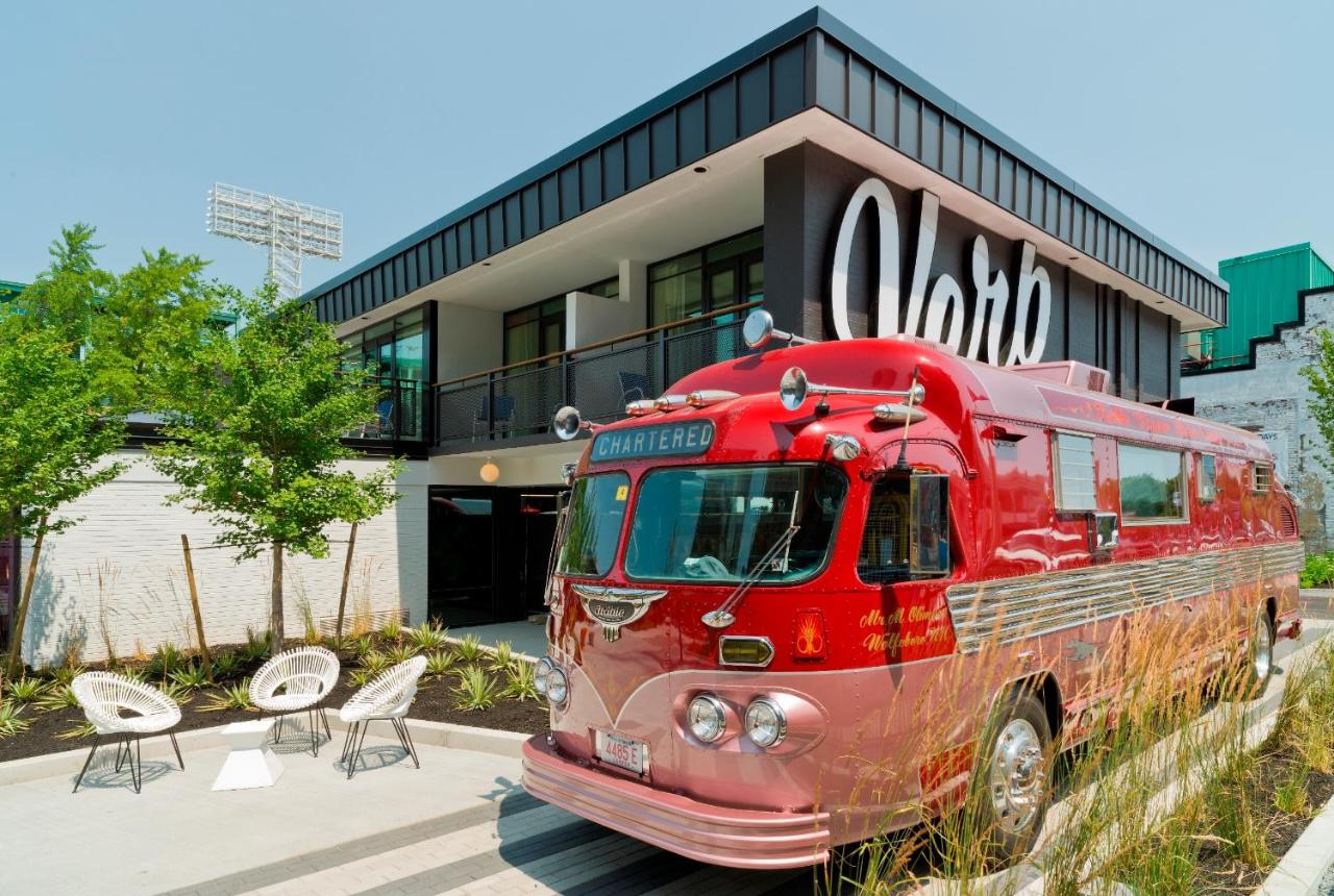 The alt text for the image should be "Vintage red bus parked in front of The Verb Hotel in Boston, Massachusetts."