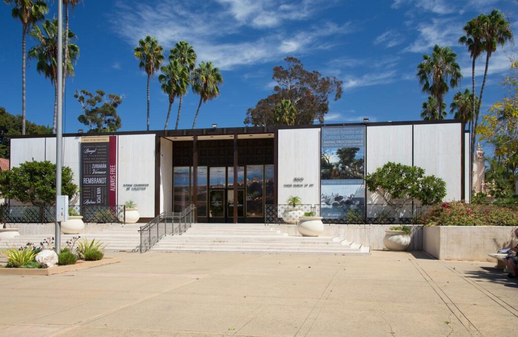 Entrance of Timken Museum of Art, San Diego, under sunny skies framed by palm trees and featuring art banners.