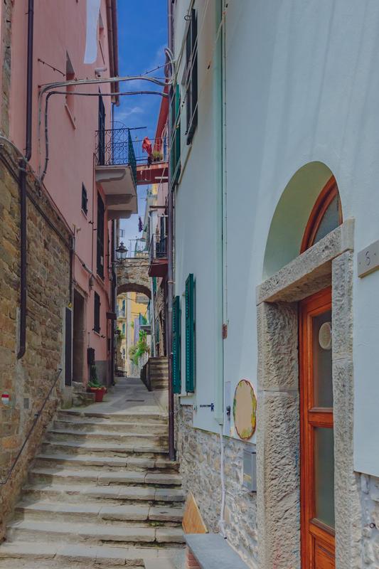 Cobblestone street in Corniglia, Italy with vibrant houses and stone steps, classic Italian architecture