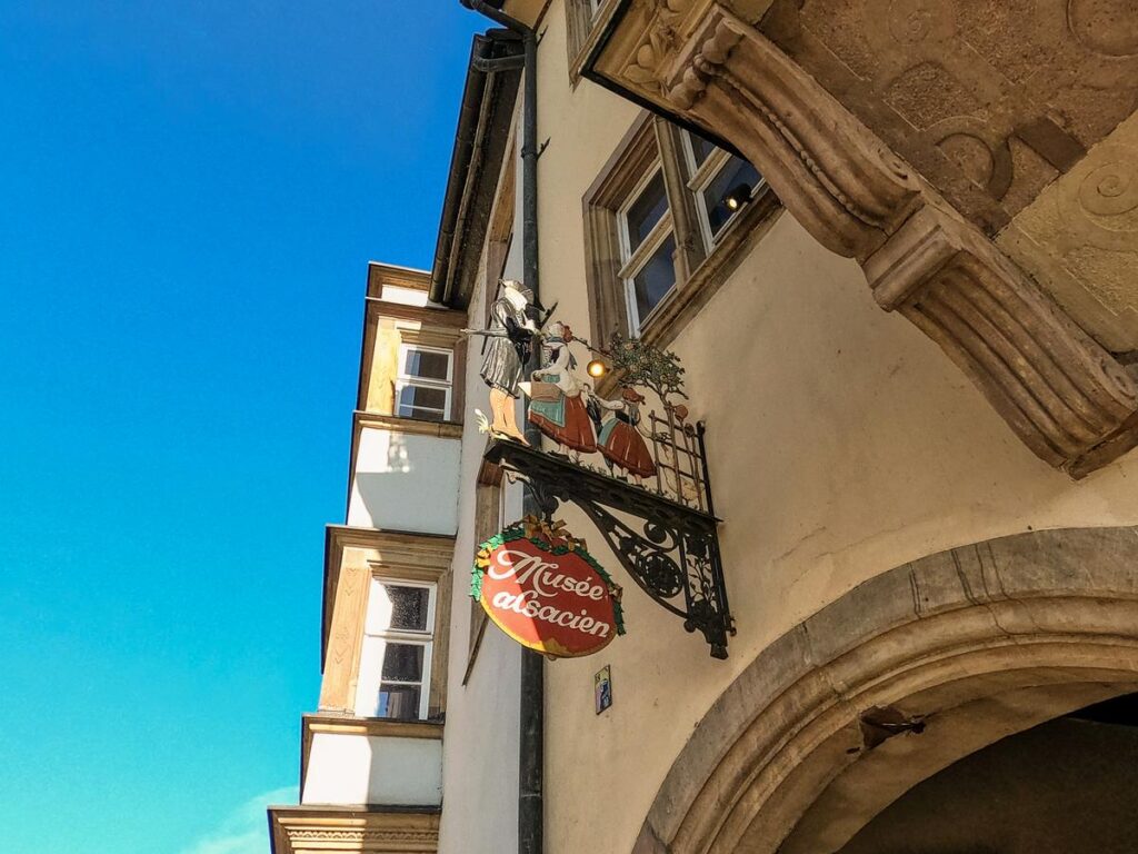Alsatian Museum sign and figures against a blue sky in Strasbourg