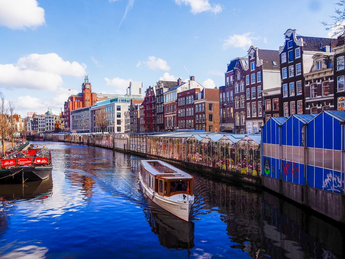 Amsterdam Bloemenmarkt with colorful flowers, canal boat, and Dutch architecture